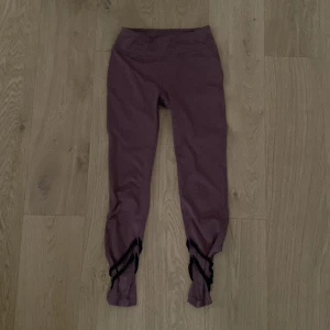Lila leggings med snörning - Snygga lila leggings med unik snörningsdetalj vid anklarna. Perfekta för en trendig look, dessa leggings är både bekväma och stiliga.