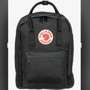 Svart ryggsäck från Fjällräven Kånken - Svart Fjällräven Kånken ryggsäck. Längd: 35cm. Bredd: 26cm. Lite fläckar men syns knappt. Handtaget högst upp saknar en knapp, se bild.