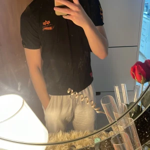 Svart t-shirt från Alpha Industries endast för 130 kr  - Säljer en svart t-shirt från Alpha Industries med orangea flammor på ärmarna. T-shirten har en rund halsringning och korta ärmar. Säljer den endast för 100 kr många undrar varför jag säljer många bra kläder för en billig pris vill bygga upp ett namn i denna appen samt för att jag också inte använder många av mina kläder så passa på och kolla vad jag har för erbjudande 