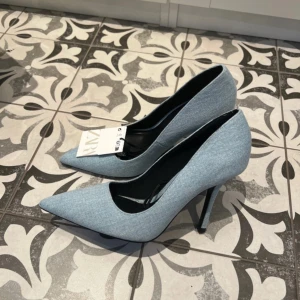 Blå pumps från Zara - Snygga blå pumps från Zara med spetsig tå och hög klack. Tillverkade i ett jeansliknande material som ger en trendig look. Perfekta för att lyfta vilken outfit som helst. Slutsålda!!!
