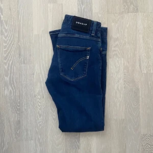  Dondup jeans  - Snygga blå jeans från Dondup med klassisk femficksdesign och guldfärgade sömmar. De har en modern passform och är perfekta för en stilren look. Jeansen har en knappgylf och är tillverkade i ett bekvämt material. Storleken är w31 längd 91 cm bredd 37 cm.