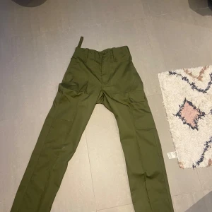 Olivgröna cargopants - Snygga olivgröna cargopants med flera praktiska fickor. Byxorna har en rak passform och är perfekta för en avslappnad stil. Tillverkade i ett slitstarkt material som passar bra för utomhusaktiviteter.