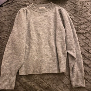 Grå stickad tröja från H&M - Säljer en mysig grå stickad tröja från H&M. Tröjan har långa ärmar och ribbade detaljer vid halsringning, storlek M