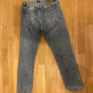 Blå jeansbyxor - Klassiska blå jeansbyxor med rak passform och hög midja. De har en dragkedja och knapp framtill samt fem fickor. Perfekta för en avslappnad stil. Ljusblå jeans från Toteme w25 l32