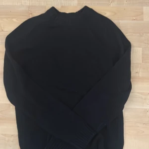 Marinblå ulltröja från East West - Säljer en stilren marinblå tröja från East West i mjuk lammull och nylon. Perfekt för kyliga dagar med sin långärmade design och ribbade detaljer vid hals och ärmslut. En klassisk och tidlös look för garderoben. Endast använt 1 gång