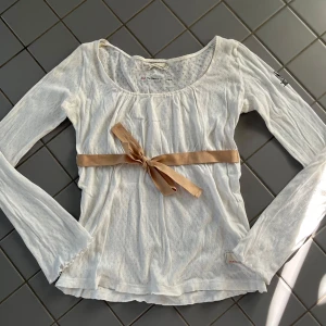 Vit långärmad topp från Odd Molly - Charmig vit långärmad topp med en beige rosett i midjan. Toppen har en rund halsringning och är tillverkad i ett lätt och luftigt material. Perfekt för en stilren och söt look. Den är ifrån Odd Molly och relvativr gammal men i fint skick. Kom gärna privat för frågor eller fler bilder ☺️
