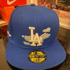 Blå keps från New Era - Snygg blå keps från New Era med broderad LA-logga och Los Angeles Dodgers-text. Kepsen har en klassisk 59FIFTY design. Helt nytt oanvänd för lite för mig, pris går diskutera