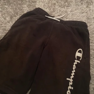 Svarta shorts från Champion - Säljer ett par svarta shorts från Champion. Perfekta för sommaren ele stil. Champion-loggan är tryckt längs benet.