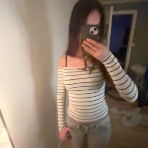 Randig offshoulder topp från Gina Tricot - Säljer en snygg randig offshoulder topp från Gina Tricot i storlek XS. Toppen är vit med svarta ränder och har långa ärmar. Perfekt för en sommardag. Jätte fint tunnt material som har ändvänds fåtal gånger. Råkade få smink på den som man ser på sista bilden. Köpte för 250kr. (ni betalar för frakten, pris kan diskuteras)