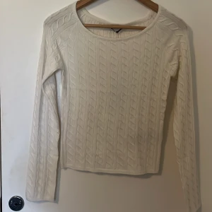 Kabelstickad topp - Säljer en stilren offwhite stickad topp med kabelstickat mönster. Toppen har långa ärmar och en rund halsringning, perfekt för alla väder. Passar bra till både jeans och kjol, beroende på vilken vibe man vill åt😍 Ny med prislappen kvar!