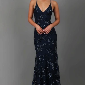 Mörkblå paljettklänning från JardinVue - Säljer min balklänning från förra året! Köpt på Jardinvue, kan hittas på Instagram. Den hsr paljettdetaljer över hela klänningen och färgen är marinblå. Har en dragkedja där bak och snören som man ser på bilden! Är som ny då jag bara använt den 1 gång. Jag är 160 och den är perfekt längd för mig! Köpt för ungefär 1500-2000kr