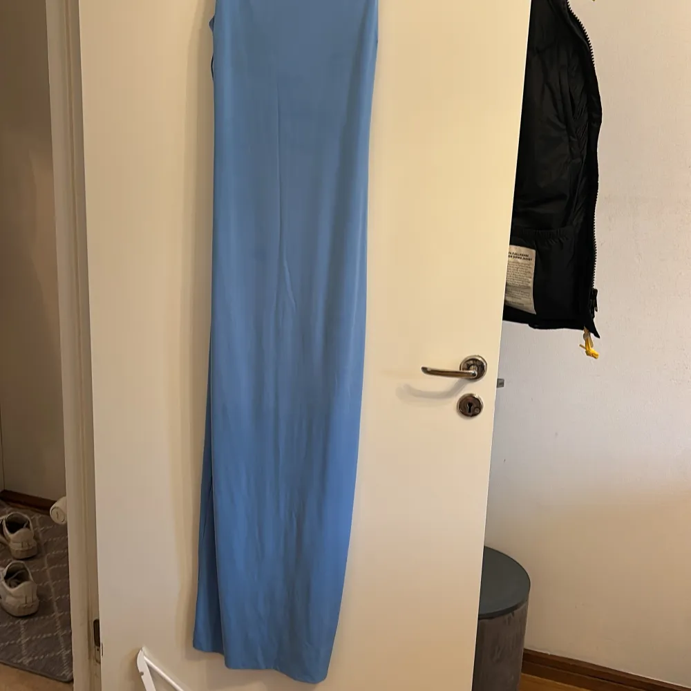 Säljer en stilren blå långklänning från Bik Bok. Klänningen har smala axelband och en enkel design som gör den perfekt för olika tillfällen. Materialet känns mjukt och bekvämt mot huden. Perfekt för dig som vill ha en elegant och minimalistisk look.. Mekot.