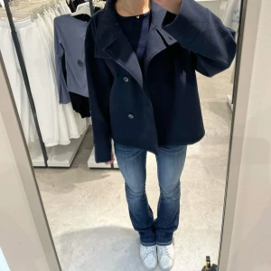 Mörkblå kappa med knappar - Snygg mörkblå kappa med stora knappar framtill. Jackan har en elegant krage och långa ärmar, perfekt för kyligare dagar. Den har en stilren design som passar till många olika outfits. Storlek 170. (Första bilden är lånad för att visa kappan på) priset går att diskutera!