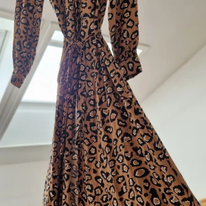 Leopardmönstrad skjortklänning med knytband - Snygg leopardmönstrad långklänning med knytband i midjan. Klänningen har långa ärmar och en klassisk krage, perfekt för en trendig look. 🐆✨