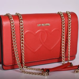 LOVE MOSCHINO väska med hjärtdetaljer - Snygg röd axelväska från Love Moschino med hjärtdetaljer på framsidan.Mycket välgjord handväska i mjukt polerat skinn.                    Justerbar guldkedja med röda    läderdetaljer som axelrem. Just denna modell har varit svår att få tag på och verkar inte tillverkas i så stor skala.                       Nypris i butik: ca 3000                                Bredd: 28 cm Höjd: 17,5