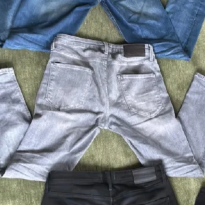 Olika jeansbyxor i olika färger - Säljer flera par jeansbyxor i olika färger. Ett par är ljusgråa, ett par är svarta och två par är blåa. Perfekta för en casual look. De har klassiska femficksmodeller och är tillverkade i jeansmaterial.