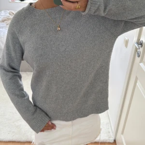 Grå stickad tröja från Vero Moda - Mysig grå stickad tröja från Vero Moda med rund hals och långa ärmar. Tröjan har ribbade muddar vid hals, ärmslut och nederkant. Perfekt för dig som gillar enkel och stilren look. Passar dig som vill ha en basic tröja att matcha med allt.