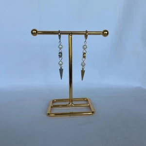 Asymmetriska örhängen med pärlor och spikes - Säljer ett par unika örhängen med cool asymmetrisk design. Ena örhänget är i silverfärg och det andra i guld, båda med vita pärlor och en spetsig spike längst ner. Perfekt för dig som vill sticka ut med edgy detaljer och mixade metaller.