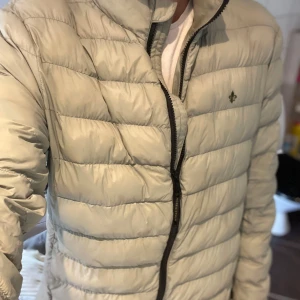 Ljusgrön pufferjacka från Morris - Snygg ljusgrön pufferjacka från Morris med quiltad design och diskret logga på bröstet. Jackan har dragkedja framtill och är lätt vadderad, perfekt för kyliga dagar. Stilren look som funkar till jeans och sneakers. Jackan har lång ärm och klassisk passform.