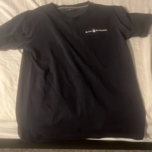 Mörkblå t-shirt från Sail Racing - Snygg mörkblå t-shirt från Sail Racing med diskret logga på bröstet och en liten logga i nacken. Klassisk rund hals och korta ärmar. Perfekt för dig som gillar stilrena och sportiga plagg. 