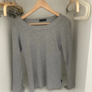 Grå långärmad tröja Vero Moda - En enkel och stilren grå långärmad tröja från Vero Moda. Tröjan har rund halsringning och är gjord i mjuk bomullsmix som känns skön mot huden. Perfekt att matcha med jeans eller kjol för en chill look.