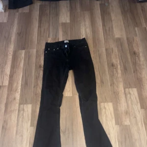Svarta flare jeans från Grunt - Säljer ett par svarta jeans från Grunt i modellen Low Flare. Byxorna har låg midja, klassisk femficksdesign och utsvängda ben för en snygg retrostil. Materialet är jeans och färgen är helsvart. Perfekta för dig som gillar en cool och trendig look.