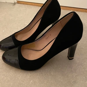Svarta pumps med lackad tå - Snygga svarta pumps med rund lackad tå och hög klack. Storlek 37