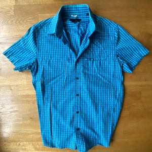 Blårutig kortärmad skjorta Riley - Snygg blårutig skjorta från Riley i tailored fit. Skjortan har korta ärmar, klassisk krage och knappar framtill. Tillverkad i mjuk bomull som känns skön mot huden. Perfekt för dig som gillar en fräsch och ungdomlig stil med lite edge.