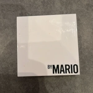 Ögonskuggspalett By Mario - Snygg ögonskuggspalett från By Mario med fyra färger: skimrande champagne, guld, beige och matt brun. Kommer i en vit fyrkantig dosa med spegel i locket, perfekt för att skapa både neutrala och glittriga looks. Helt oanvänd och nypris är 329 kr.