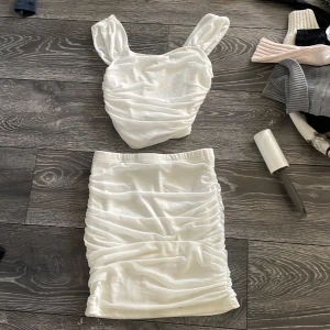 Vit omlott linnetopp med breda axelband - Säljer en vit omlott linnetopp med breda axelband och snygga rynkade detaljer. Toppen har en mjuk, glansig finish och är perfekt för dig som gillar en clean och fräsch look. Materialet känns lent och har ett lätt fall. Passar dig som vill sticka ut med en enkel men trendig topp.