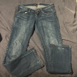 Lågmidjade jeans  - Säljer ett par lågmidjade jeans i blå tvätt. Jeansen har bootcut liknande passform och fem fickor. Perfekta för dig som gillar en tidlös look med lite extra vidd vid benslutet.
