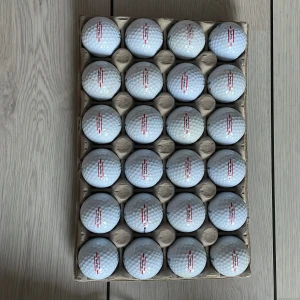24 stycken titleist trufeel golfbollar  - Bilderna visar ett flertal golfbollar av märket TruFeel, snyggt uppradade i en kartong. Perfekt för dig som vill ta din golf till nästa nivå, oavsett om du är nybörjare eller proffs. Bollarna ser ut att vara i gott skick och redo för spel på banan.