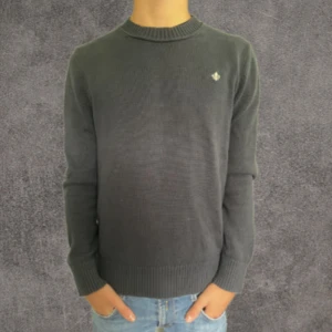 Mörkgrå stickad tröja från Morris - Snygg mörkgrå stickad tröja från Morris med rund hals och diskret logga broderad på bröstet. Tröjan har ribbade muddar vid ärmslut och nederkant, vilket ger en clean och stilren look. Perfekt till jeans och sneakers.