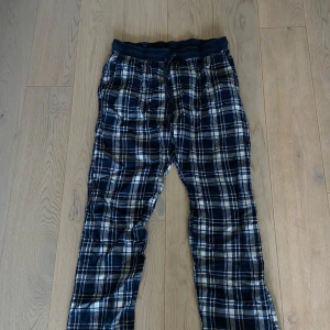 Rutig pyjamasbyxa från Hampton Republic - Säljer ett par sköna pyjamasbyxor från Hampton Republic i storlek M men skulle säga att det är mer som S och passar även XS om man vill att de ska sitta lite större.  Byxorna är mörkblå med vitt och grått rutmönster, har elastisk midja med snörning och är gjorda i mjukt bomullsmaterial. Perfekta för chill hemma eller häng med kompisar.