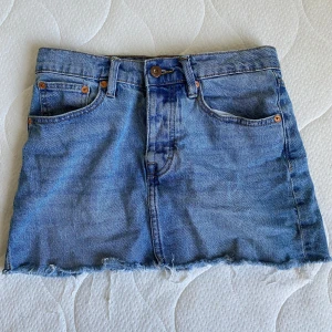 Blå jeanskjol från 157 - Säljer en blå lågmidjad jeanskjol från 157, modell MADDY. Jag har klippt kjolen kortare vilket ger den en fransig nederkant, den har en rad knappar istället för dragkedja. Passar till allt och är superenkel att styla. 📏Mått: ca 39-40 cm rakt över midjan, ca 32 cm lång.