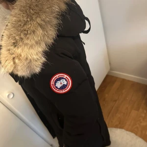 Svart lång dunjacka Canada Goose - Dragkedjan behöver bytas samt sista knappen längst ner fungerar inte. Storlek L 