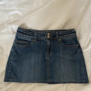 Jeanskjol  - Snygg kort jeanskjol från KappAhl. Dubbla metallknappar i midjan. Perfekt för dig som vill ha en kort skön kjol. Jeans tyget är ganska mjukt!