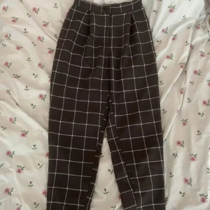 Bruna rutiga kostymbyxor - Bruna rutiga kostymbyxor från H&M i strl 34. Byxorna har vitt rutmönster, hög midja och knäppning fram med knapp!💞