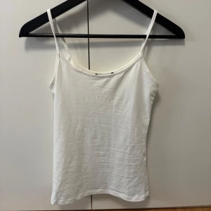 Vit linnetopp från Zara - Enkel och stilren vit linnetopp från Zara med smala axelband. Toppen är ärmlös och har en rak passform, perfekt att matcha med jeans eller kjol. Tillverkad i lite silkigt material vilket är så skönt mot huden!