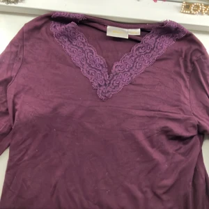 Lila långärmad topp med spets Gina Tricot - Supersnygg lila långärmad topp från Gina Tricot med v-ringning och dekorativ spetskant runt halsen. Mjuk och skön i bomullsmix, perfekt till lager-på-lager eller som den är. Enkel att styla med både jeans och kjol. använd några gånger! Även perfekt till hösten med dess vinröda färg!😻😻