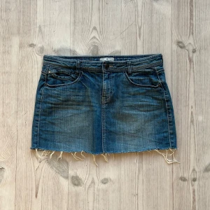 Blå lågmidjad jeanskjol  - Lågmidjad jeanskjol från Tom Tailor som jag har gjort om från en längre kjol. Fint skick. Tvärs över midjan är det 41 cm och längs med sidan är det 33 cm. Använd gärna köp nu!