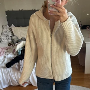 Stickad hoodie bikbok  - Supermysig vit hoodie från BikBok i ribbstickat material. Tröjan har dragkedja framtill, huva och långa ärmar. Perfekt för lager på lager och chill dagar. Snygg och enkel att matcha med jeans eller leggings.