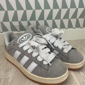 Adidas Campus grå/vita sneakers - Snygga Adidas Campus sneakers i grå färg. Tjena! Jag säljer nu mina campus i ett riktigt fint skick, skorna är använda cirka 7 gånger och därför inga defekter eller skador. Hör av dig vid intresse!