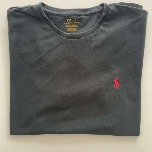 Svart t-shirt från Polo Ralph Lauren - Äkta Ralph Lauren T-shirt – Svart, Storlek M  Klassisk svart T-shirt från Ralph Lauren, i bra skick. Stilren design med broderad logga – perfekt till både vardag och festligare tillfällen.  ✔️ Storlek: M ✔️ Färg: Svart ✔️ Skick: Bra, sparsamt använd ✔️ 100 % äkta vara  Skickas snabbt & säkert! 📦 Passa på innan den försvinner – begränsat antal!