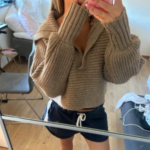Brun/beige stickad tröja  - Supermysig beige stickad tröja med bred krage och croppad passform. Tröjan har långa, vida ärmar och ribbade detaljer vid ärmslut och krage. Perfekt för hösten 💗 
