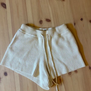 Beige ribbade shorts från Soft Goat - Supermysiga och sköna skickade ribbade shorts i beige från Soft Goat. Dragsko i midjan och är stickade i ett mjukt material. Snygg loose fit och fickor på sidorna. Nästan aldrig använda.