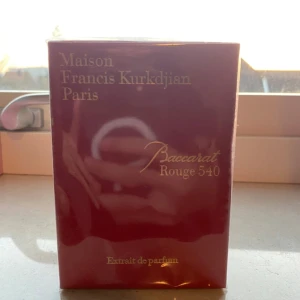 Baccarat Rouge 540 Extrait de Parfum - Lyxig parfym från Maison Francis Kurkdjian, Baccarat Rouge 540 Extrait de Parfum. Kommer i en elegant, djup röd kartong med guldfärgad text. Förpackningen är rektangulär och inslagen i plast. Perfekt för dig som gillar exklusiva dofter och snygg design.