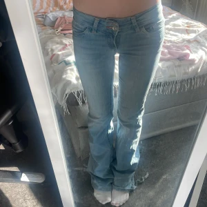 Ljusblå jeans från Nelly med brodyr - Säljer ett par ljusblå jeans från Nelly med raka ben och snygg rosa brodyr på bakfickorna. Jeansen har klassisk femficksdesign och detaljer i rosa vid sömmarna. Perfekta för dig som vill ha en chill och trendig look.