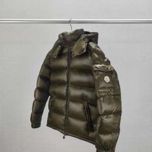 Moncler Jacka - Köp görs via Instagram - Säljer en olivgrön dunjacka från Moncler med glansig finish och klassisk pufferstil. Jackan har huva, dragkedja framtill och fickor med dragkedja. Moncler-logga på ärmen och quiltad design gör den både snygg och funktionell. Köp görs via Instagram Maison la drippo