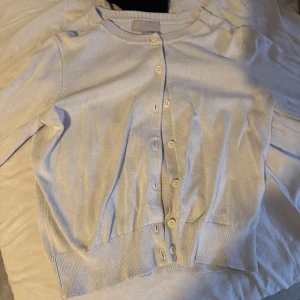 vit kofta från H&M, storlek S - En stilren vitkofta från H&M i storlek S. Koftan har rund halsringning, långa ärmar och knäppning framtill med matchande knappar. Tillverkad i mjukt, stickat material som är perfekt för lager-på-lager. Enkel och clean look som funkar till det mesta. lite urtvättat och har gått mer åt de gråa hållet!